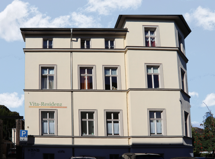 Mehrstöckiges Gebäude der Vita-Residenz mit parkenden Autos und blauen Himmel im Hintergrund.